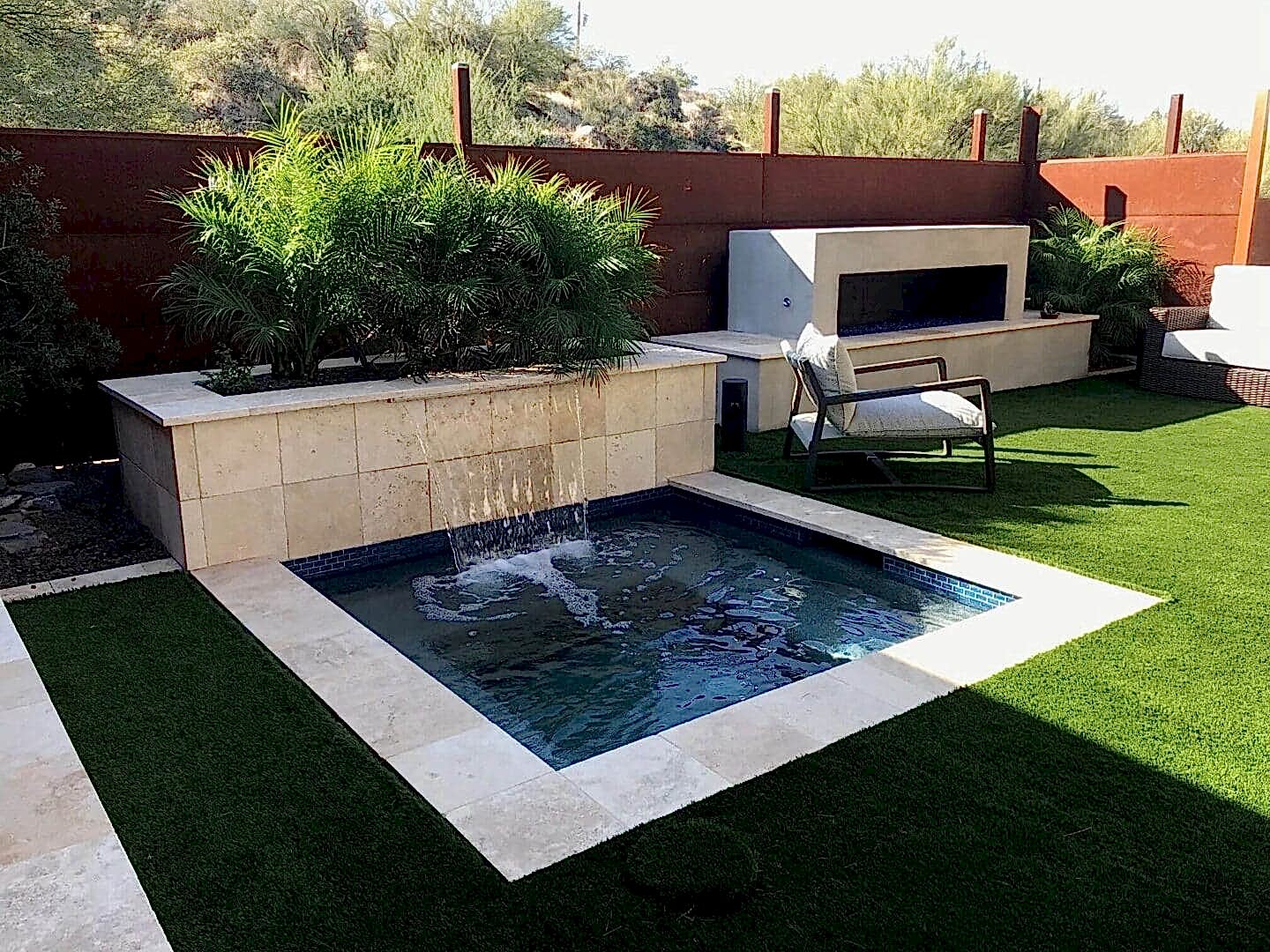 A small pool with water jets and a fire place.