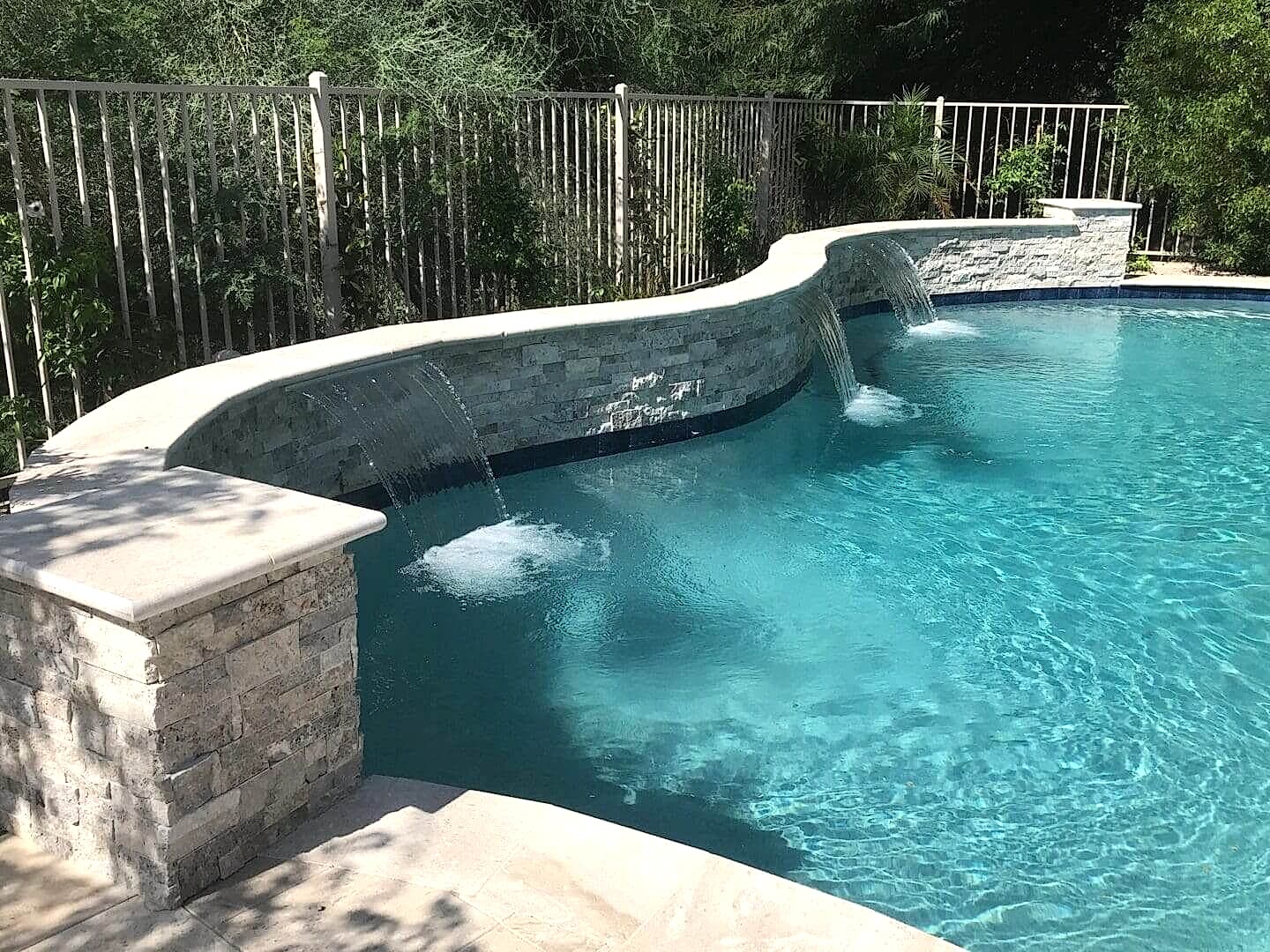 A swimming pool with water falling from the side.