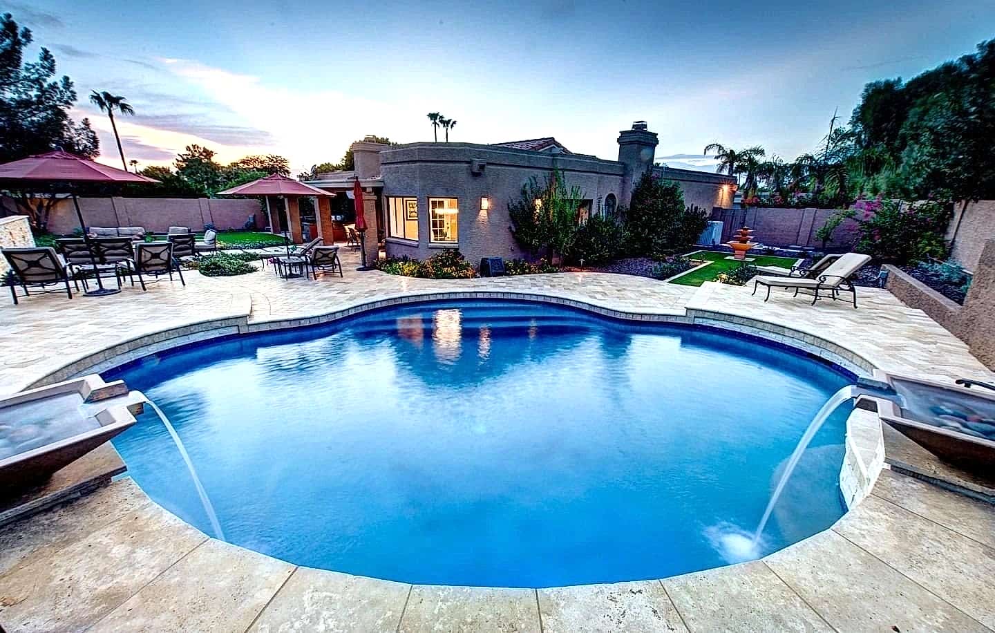 A pool with water jets and a house in the background.