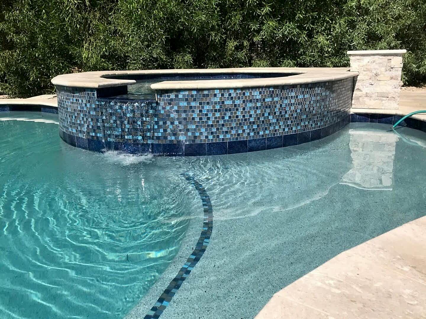 Blue tile spa with waterfall in pool.