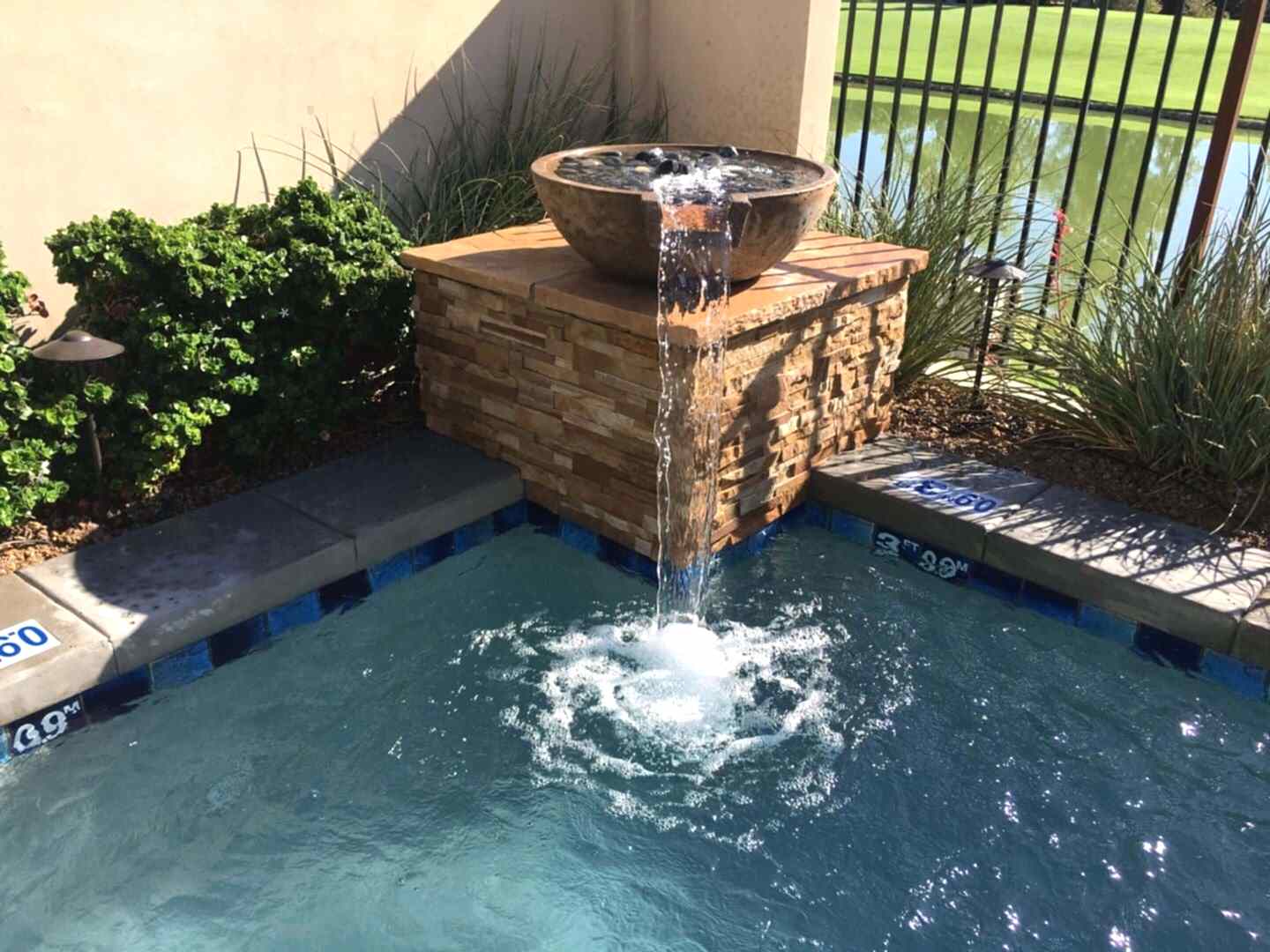 Stone bowl water feature in pool.