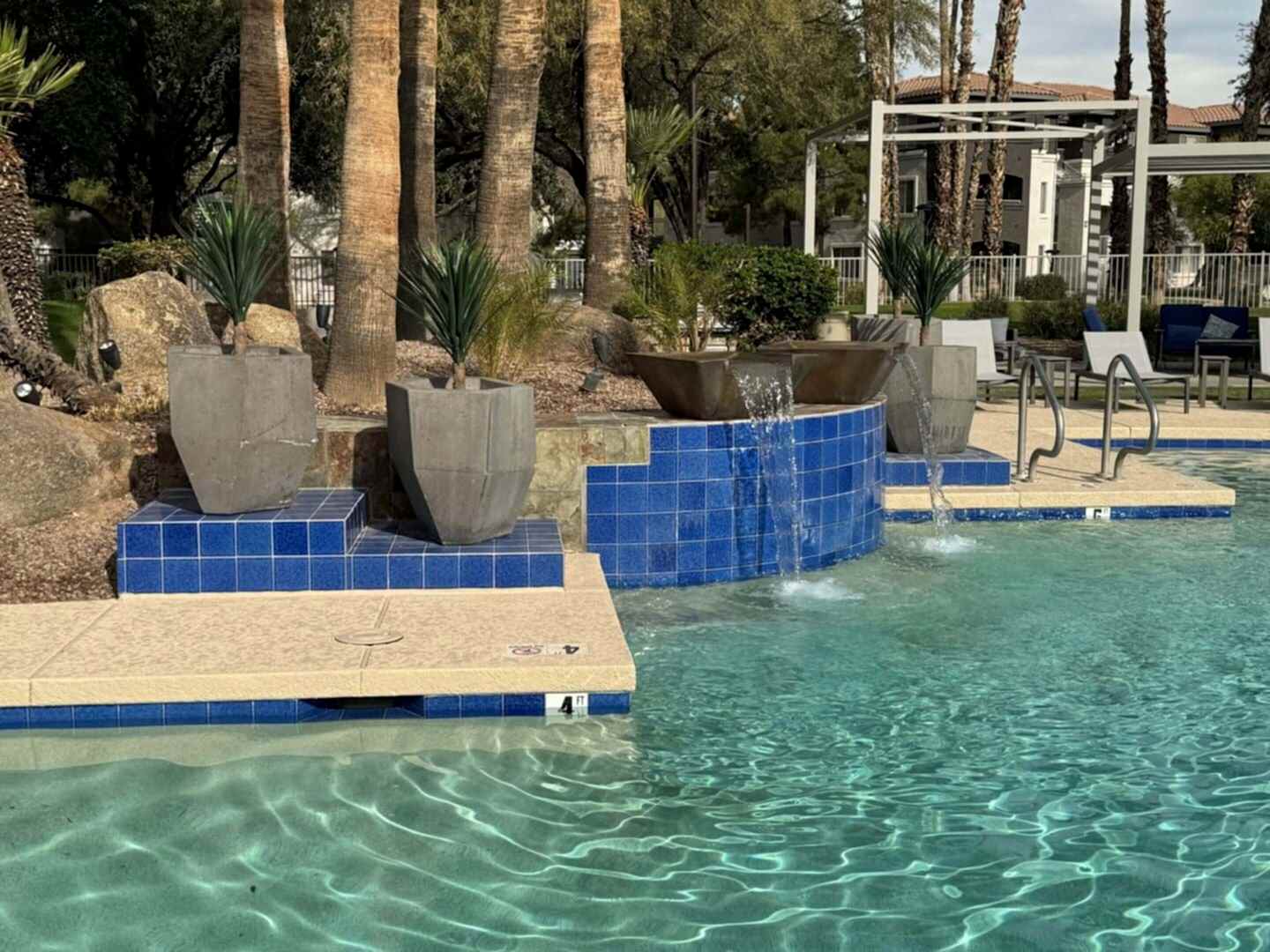 Poolside fountain with plants and blue tiles.