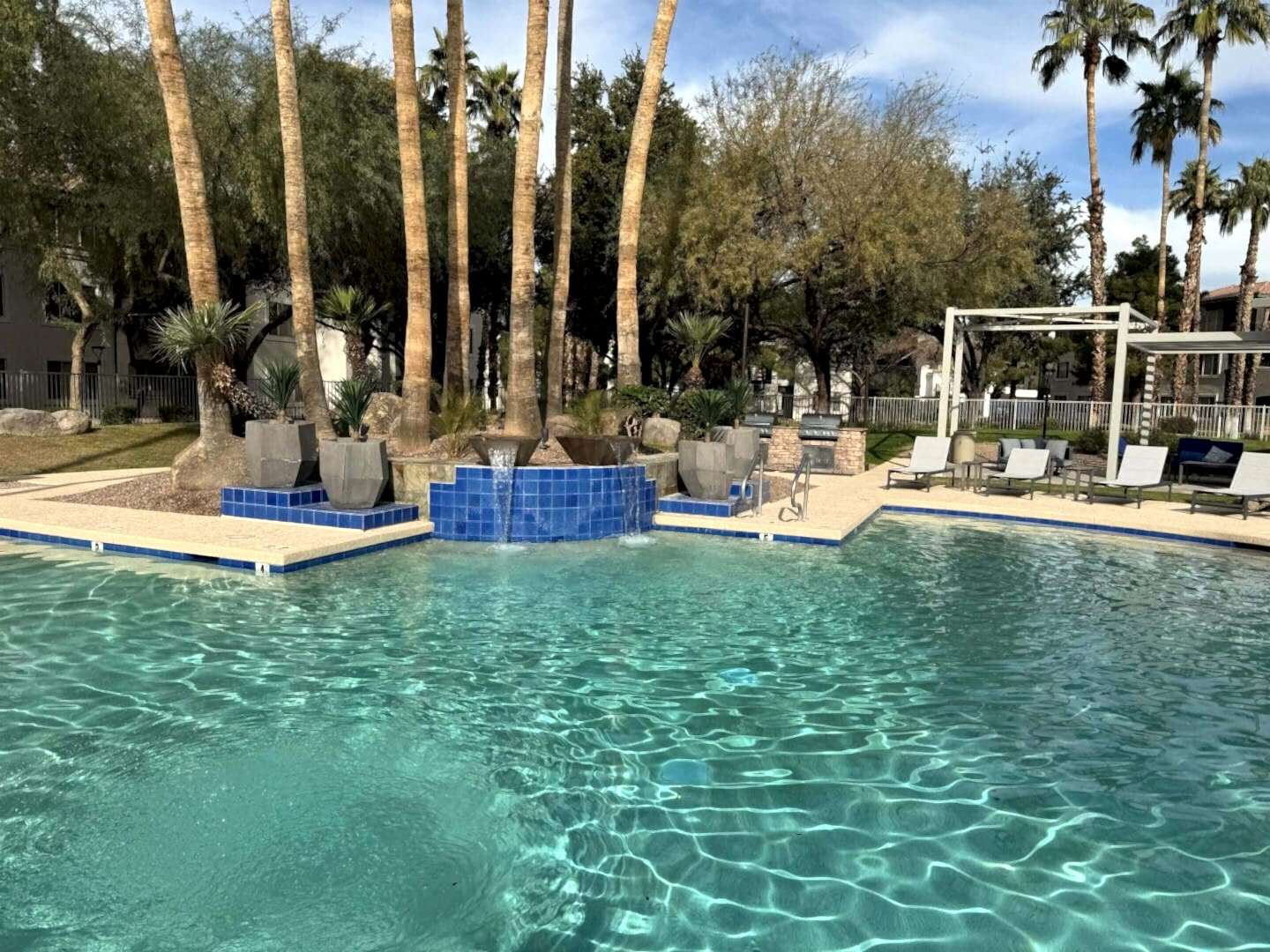 Resort pool with palm trees and waterfall.