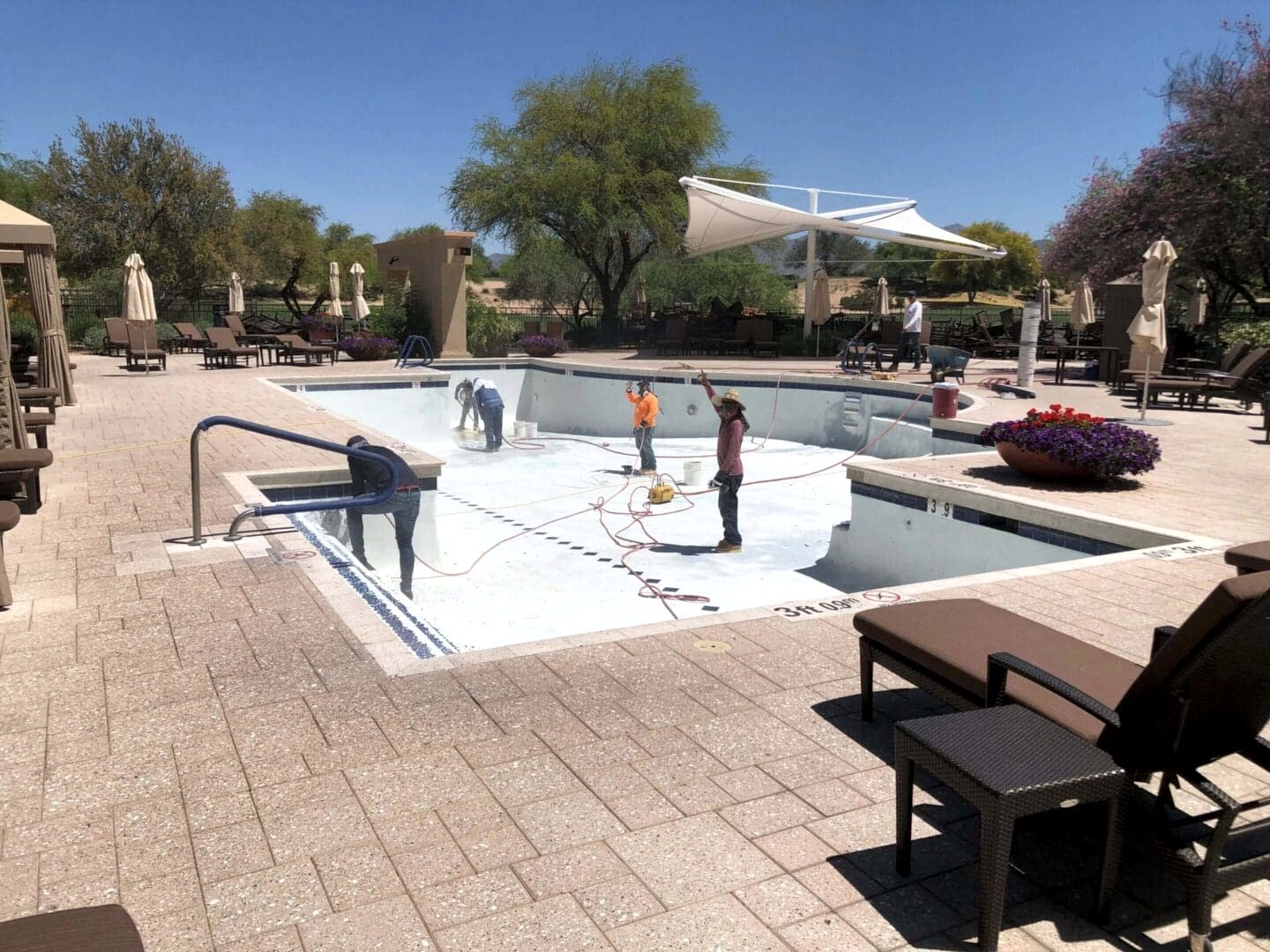 Workers cleaning empty swimming pool.