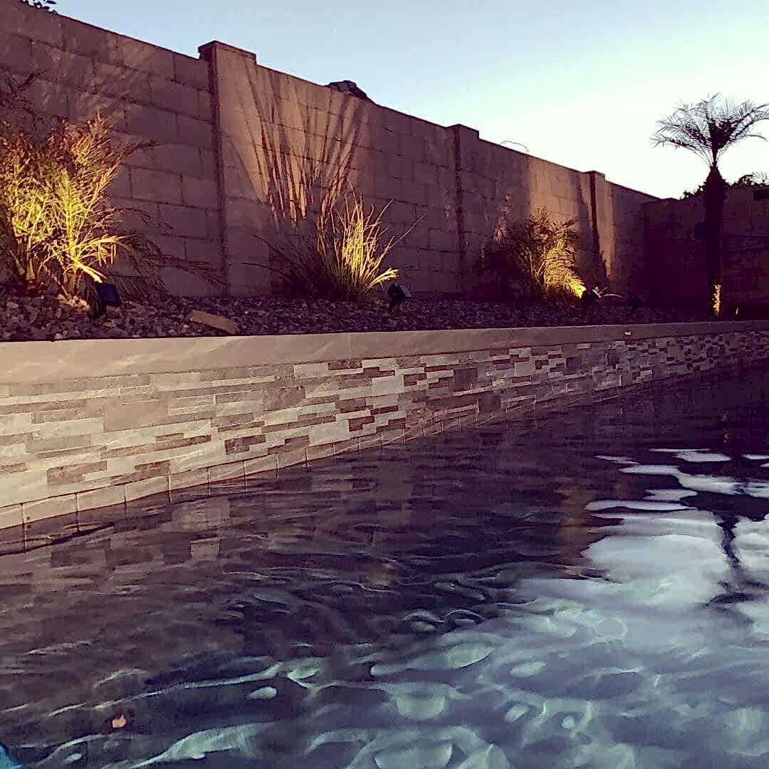 Here's an alt tag for the image: Evening poolside scene with lighting.