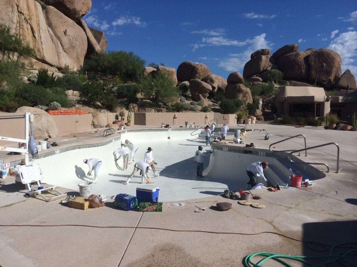 Workers repainting a pool in desert setting.