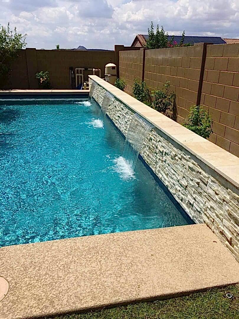 Stone waterfall feature in a blue pool.