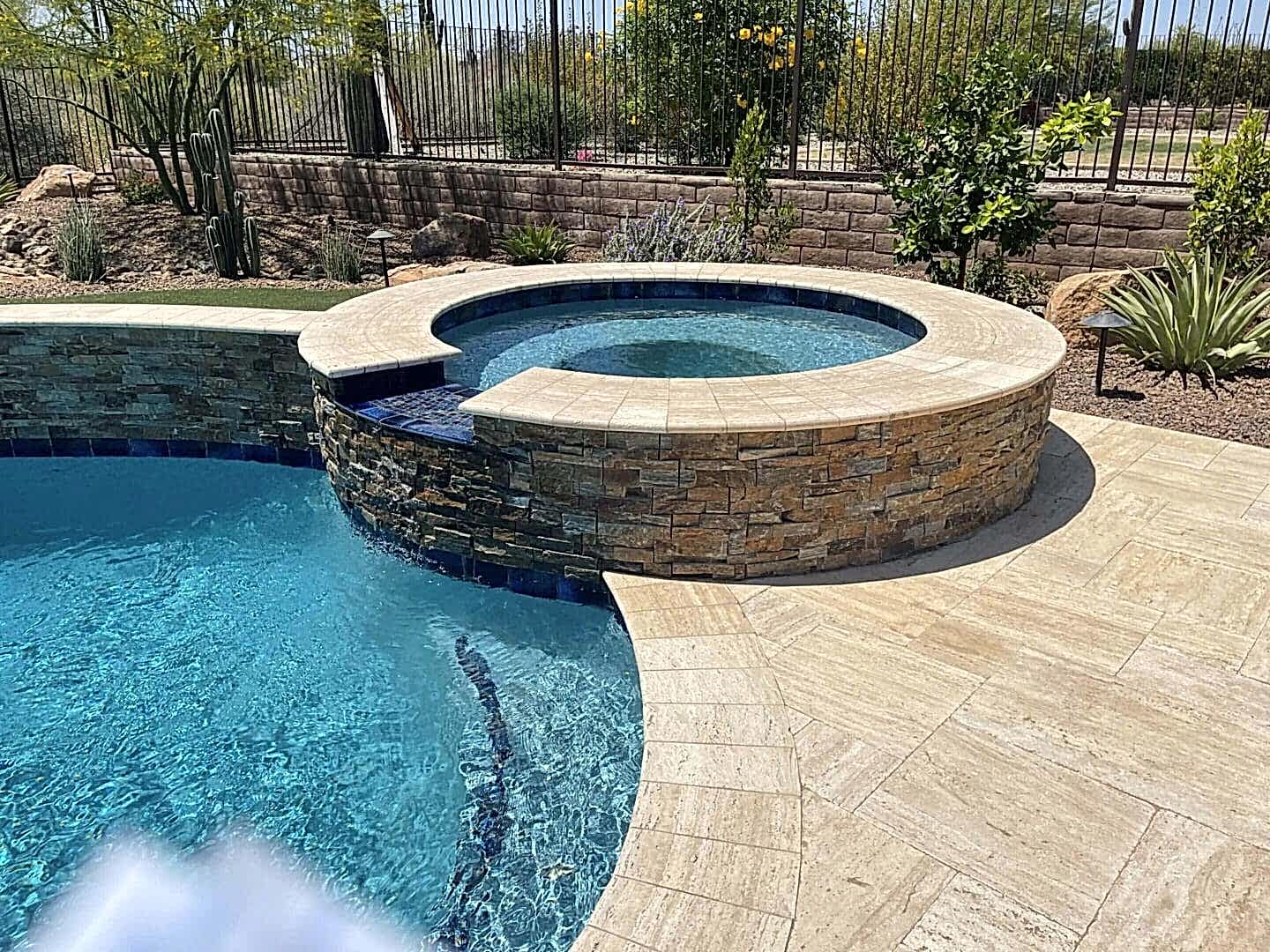 Stone-clad spa spilling into pool.