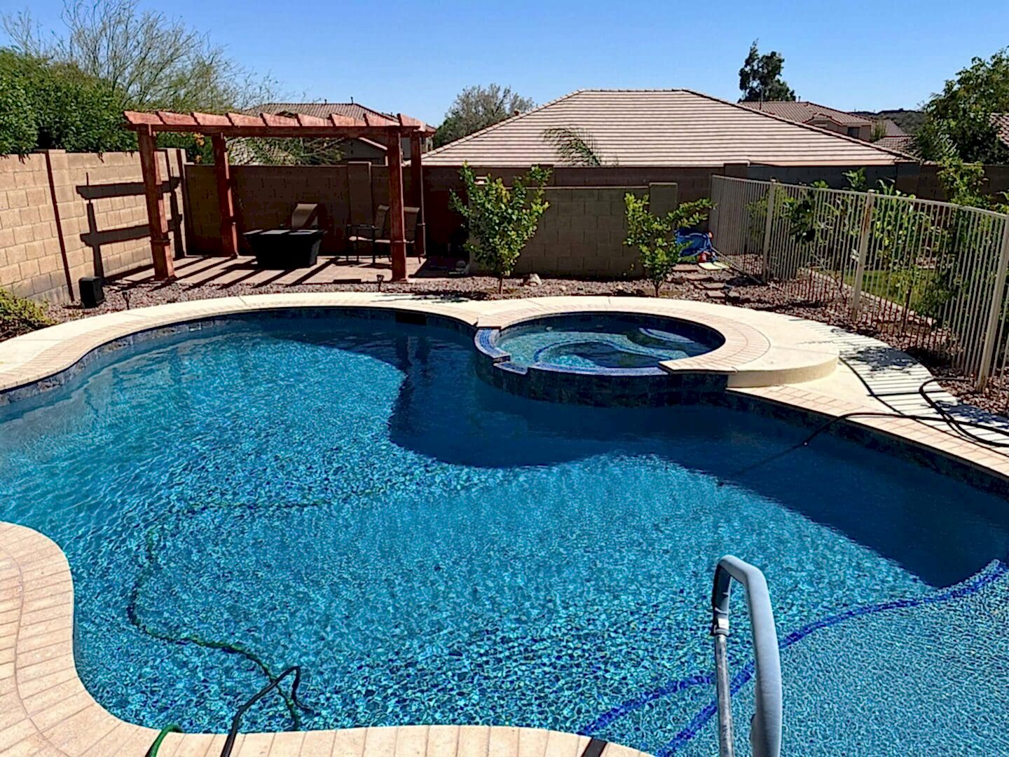 Sparkling blue pool with spa and pergola.