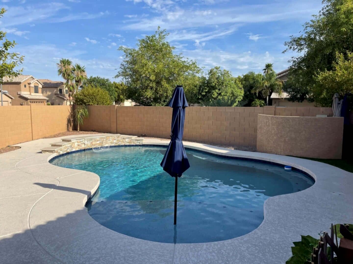 Blue umbrella over backyard swimming pool.
