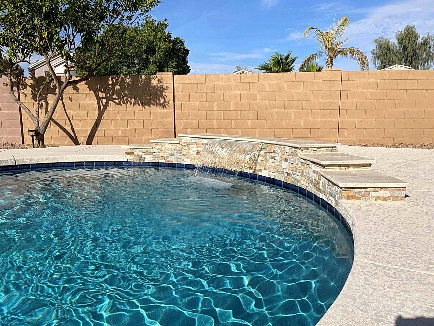 Stone waterfall feature in backyard pool.
