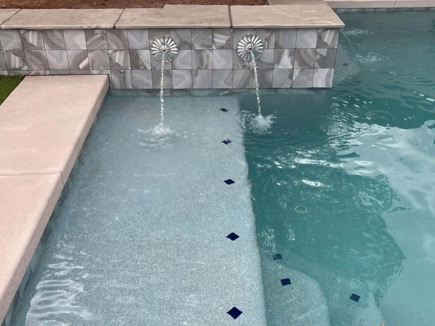 Here's an alt tag for the image: Two pool fountains and tile accents.