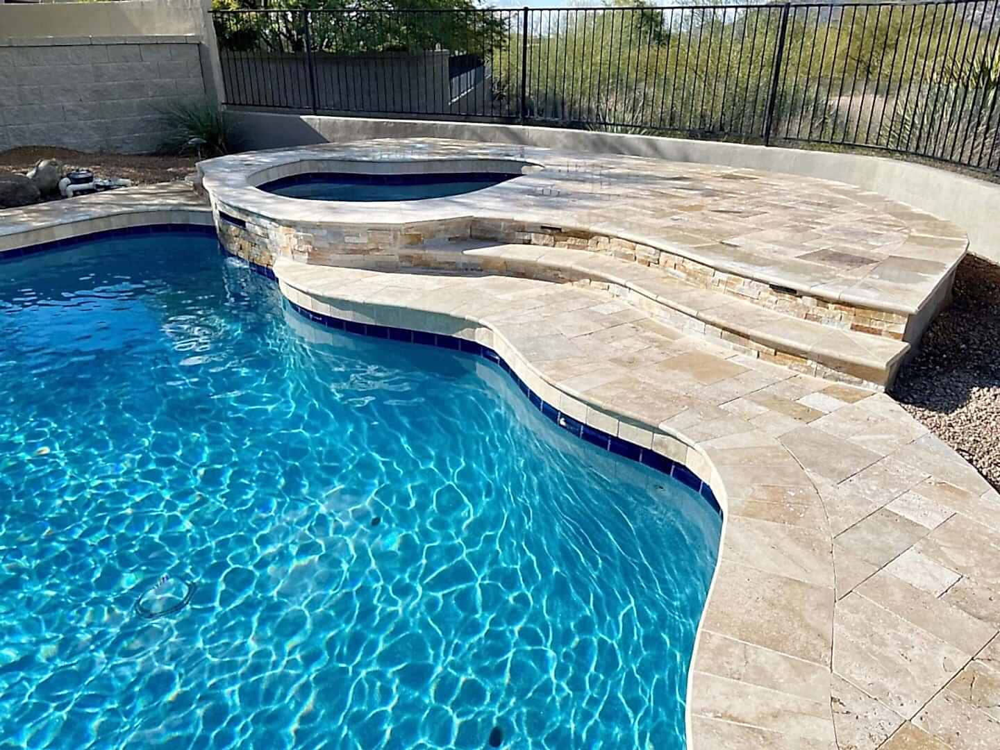 Here's an alt tag for the image: Blue pool with spa and stone steps.