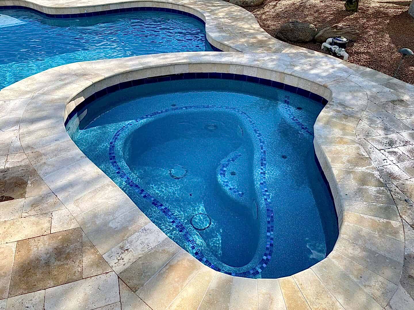 Here's an alt tag for the image: Blue pool spa with tan tile.