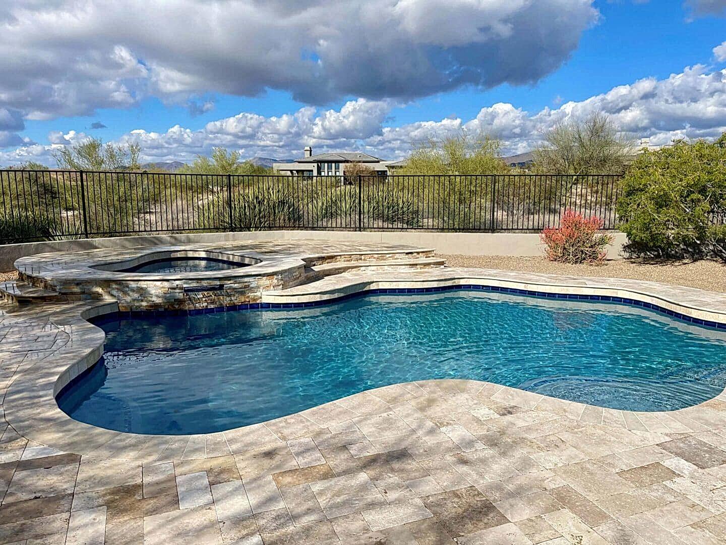 Here's an alt tag for the image: "Luxury pool and spa with stone patio"