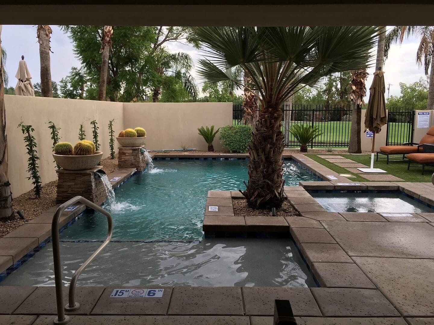 Resort pool with palm trees and cacti.