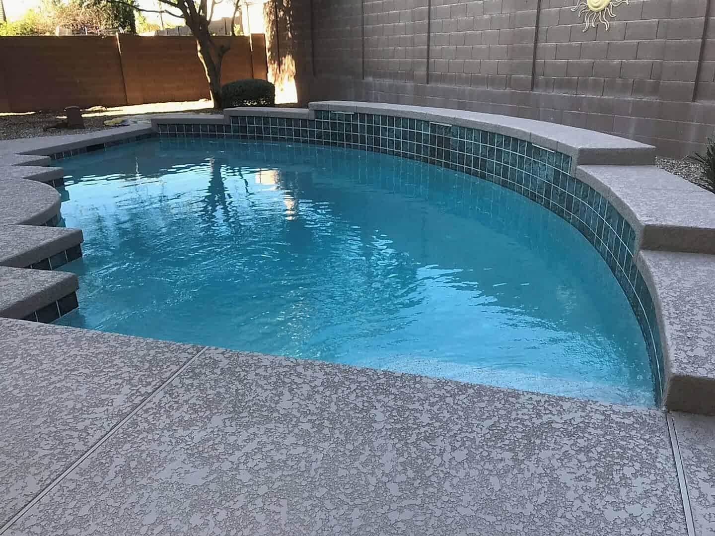 Swimming pool with gray concrete deck.