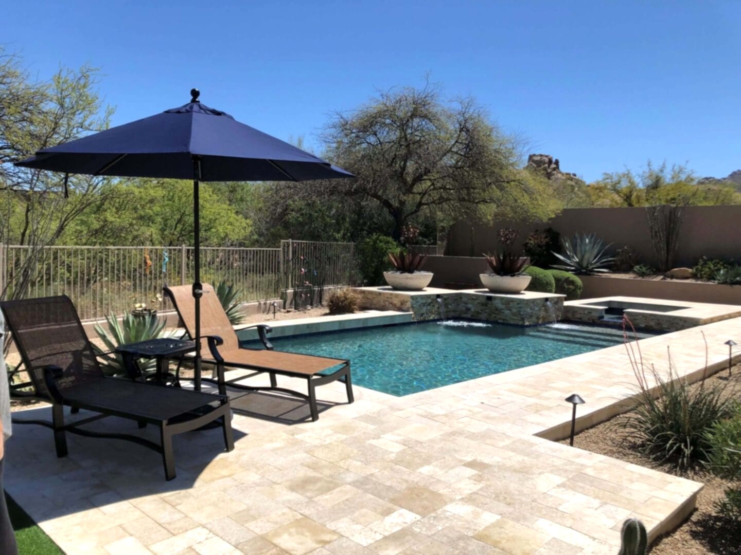 Poolside patio with lounge chairs and umbrella.