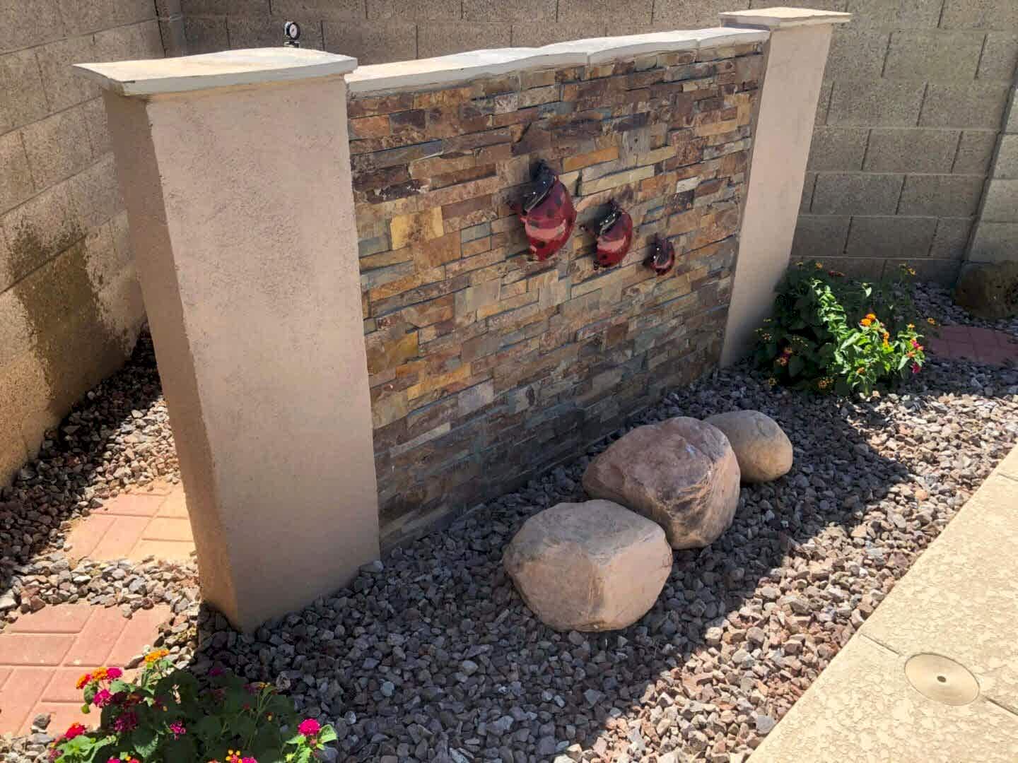 Stone wall with ladybug art and rocks.